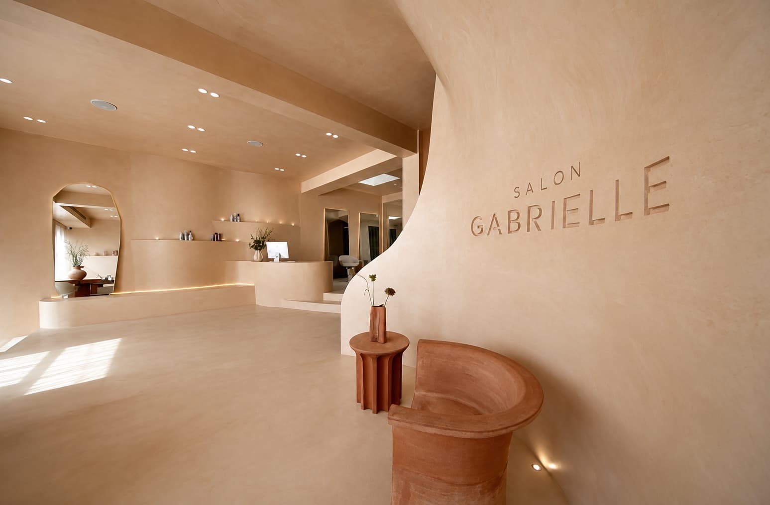 Polished plaster reception wall and curved joinery at Salon Gabrielle, Melbourne