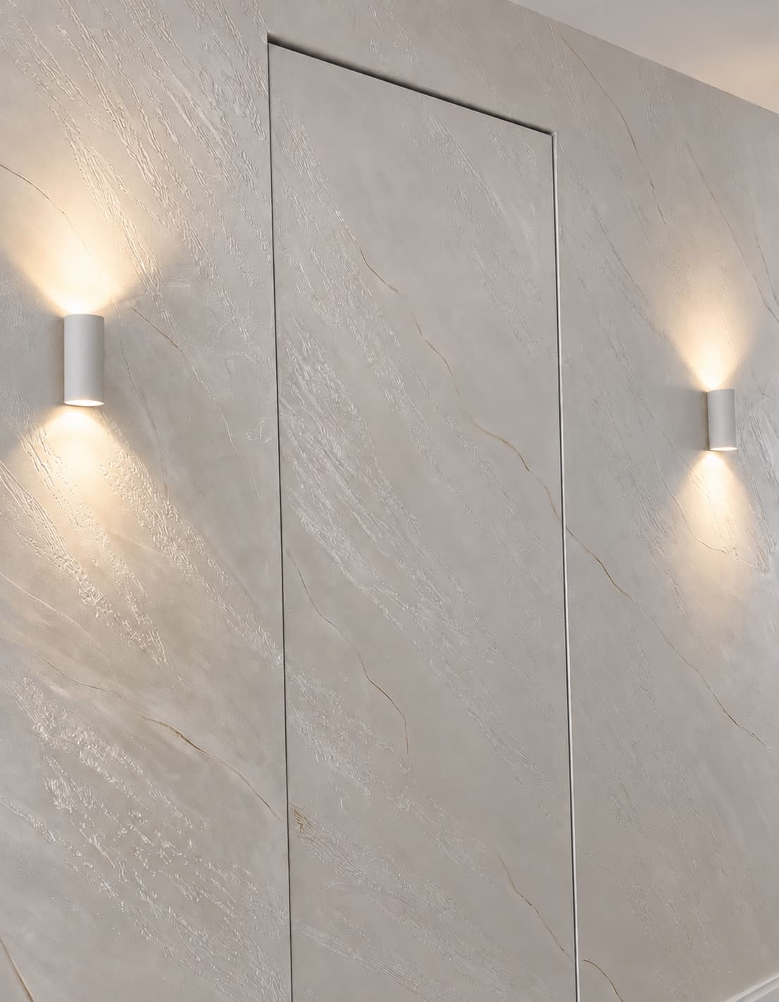 Split-stone Venetian plaster wall with a concealed door and wall uplighting